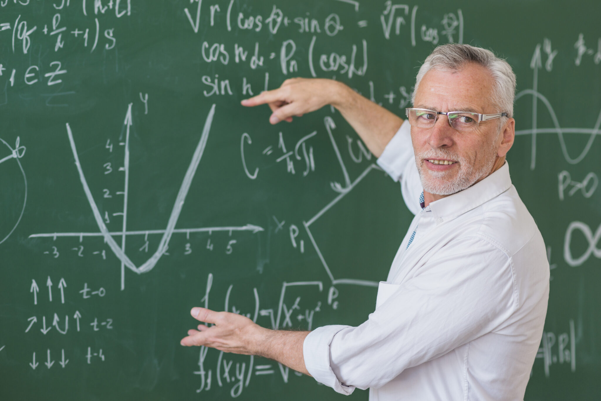 senior-teacher-glasses-explaining-math-example-green-chalkboard